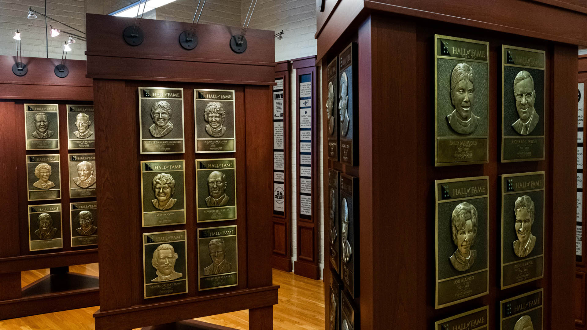 Triangular wooden stands in the Hall of Fame feature gold tone plaques with relief sculptures of people's faces